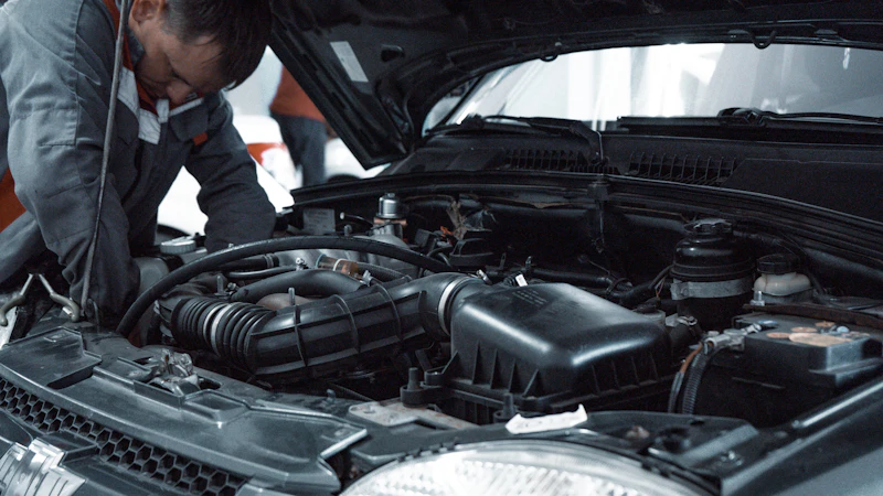 Mecanic verificând compartimentul motor al unei mașini în atelier